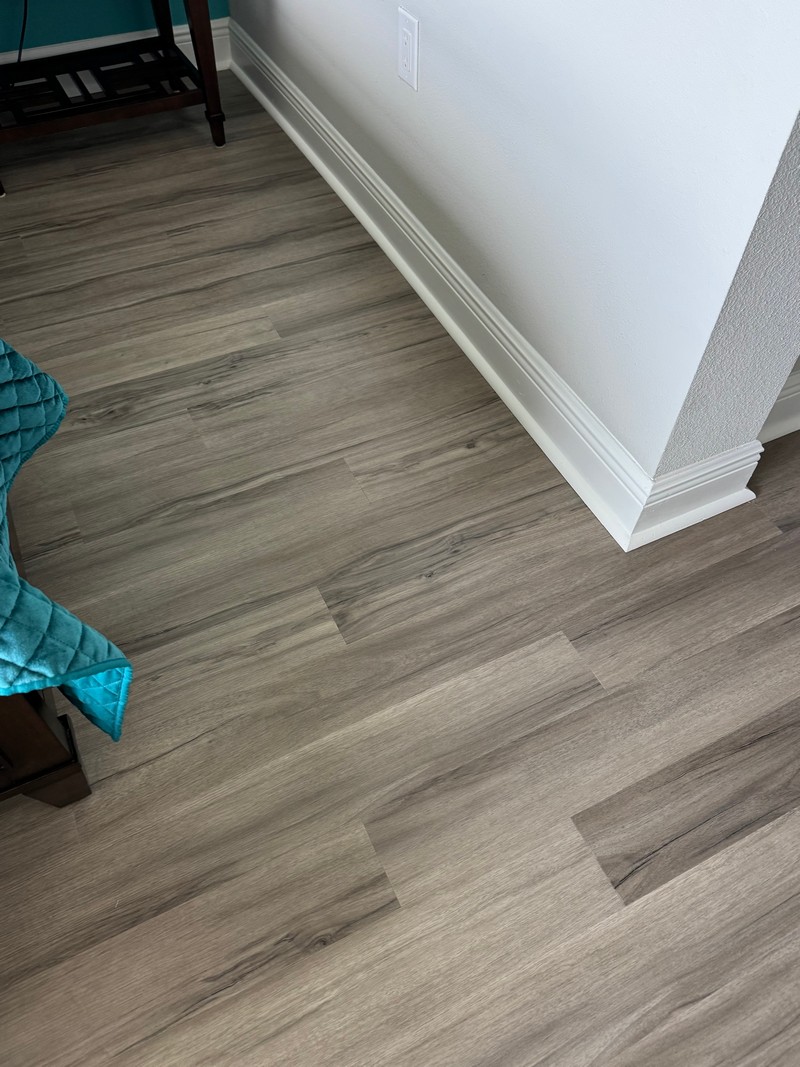 Ashton Woods Oak COREtec Luxury Vinyl flooring in the corner of a room where a wall and baseboard are visible